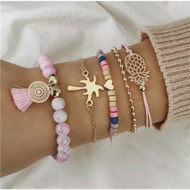 Pink stacking beaded bracelet with gold heart, filigree pineapple, palm tree, tassle charm