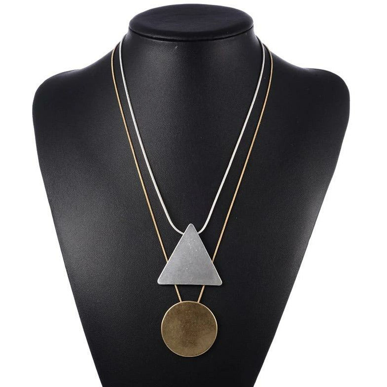 layered gold and silver necklace with geometric triangle circle pendants. 